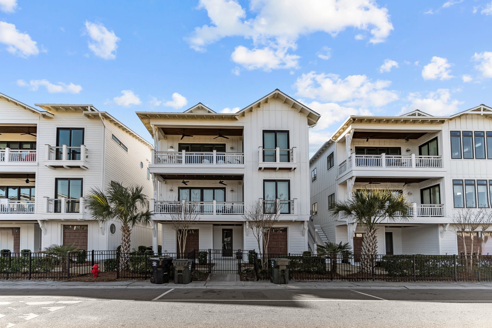 Modern coastal townhomes with balconies and palm trees.
