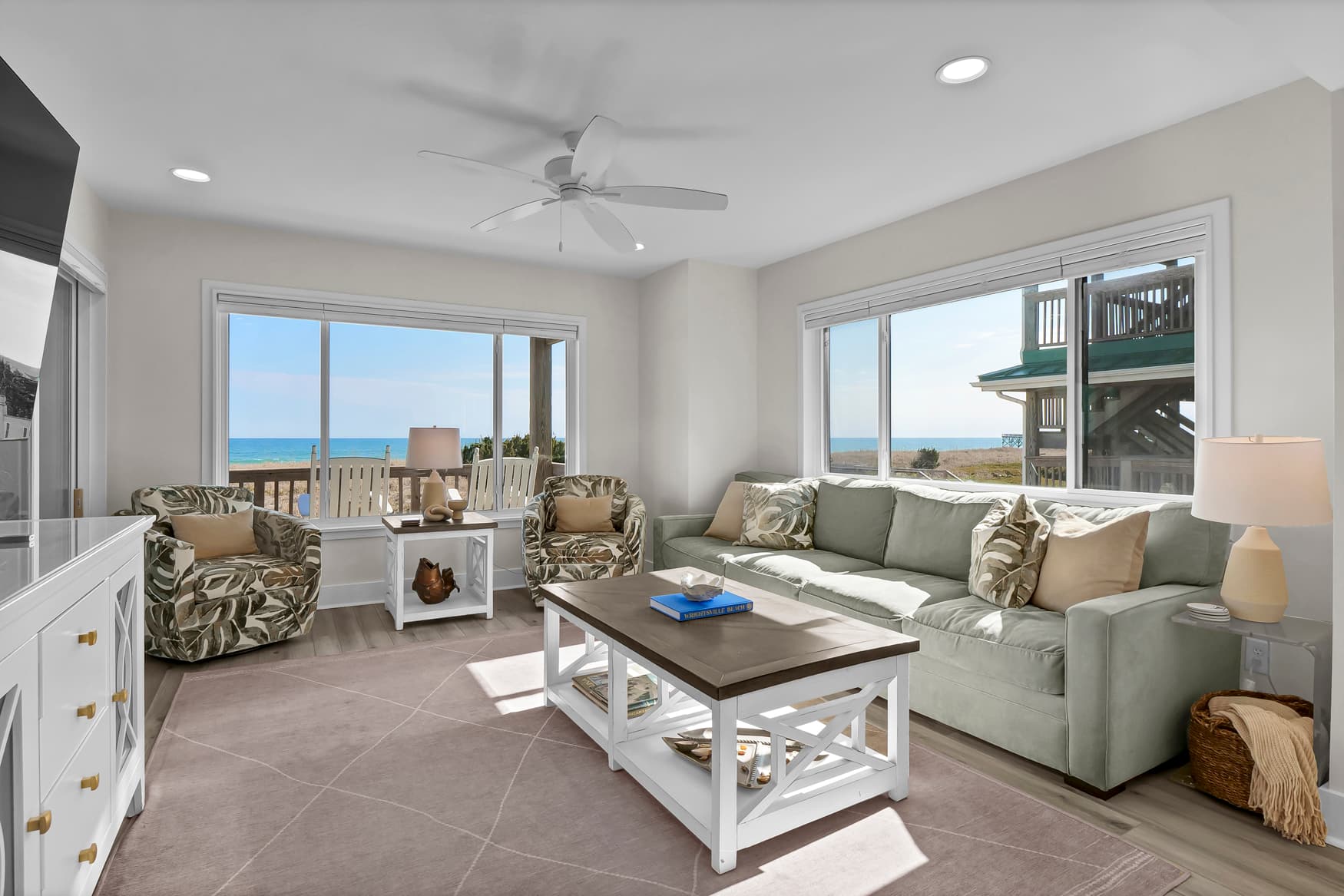 Relax in your coastal living room with stunning ocean views through oversized windows and cool sea breezes from the ceiling fan.