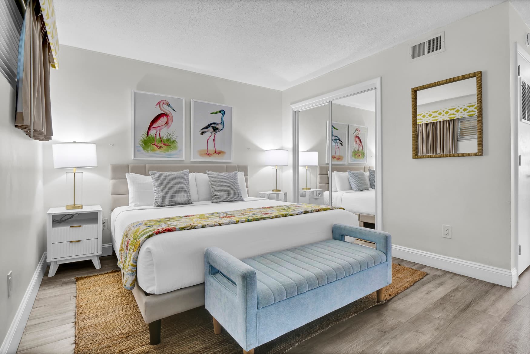 Relax in your beautifully appointed bedroom featuring a plush king bed, coastal bird artwork, and elegant blue bench seating - your perfect retreat after a day of adventures.