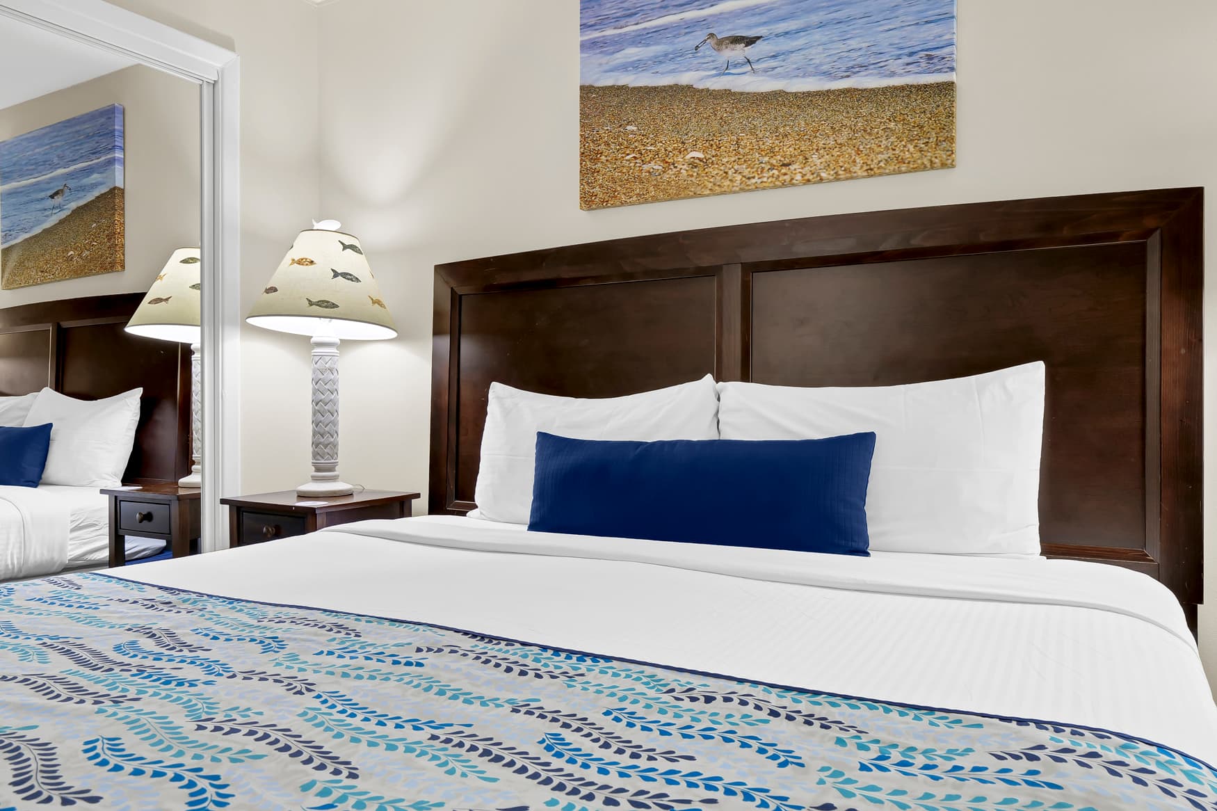 Rest in your coastal-themed bedroom with crisp linens and beach artwork creating a serene seaside atmosphere.
