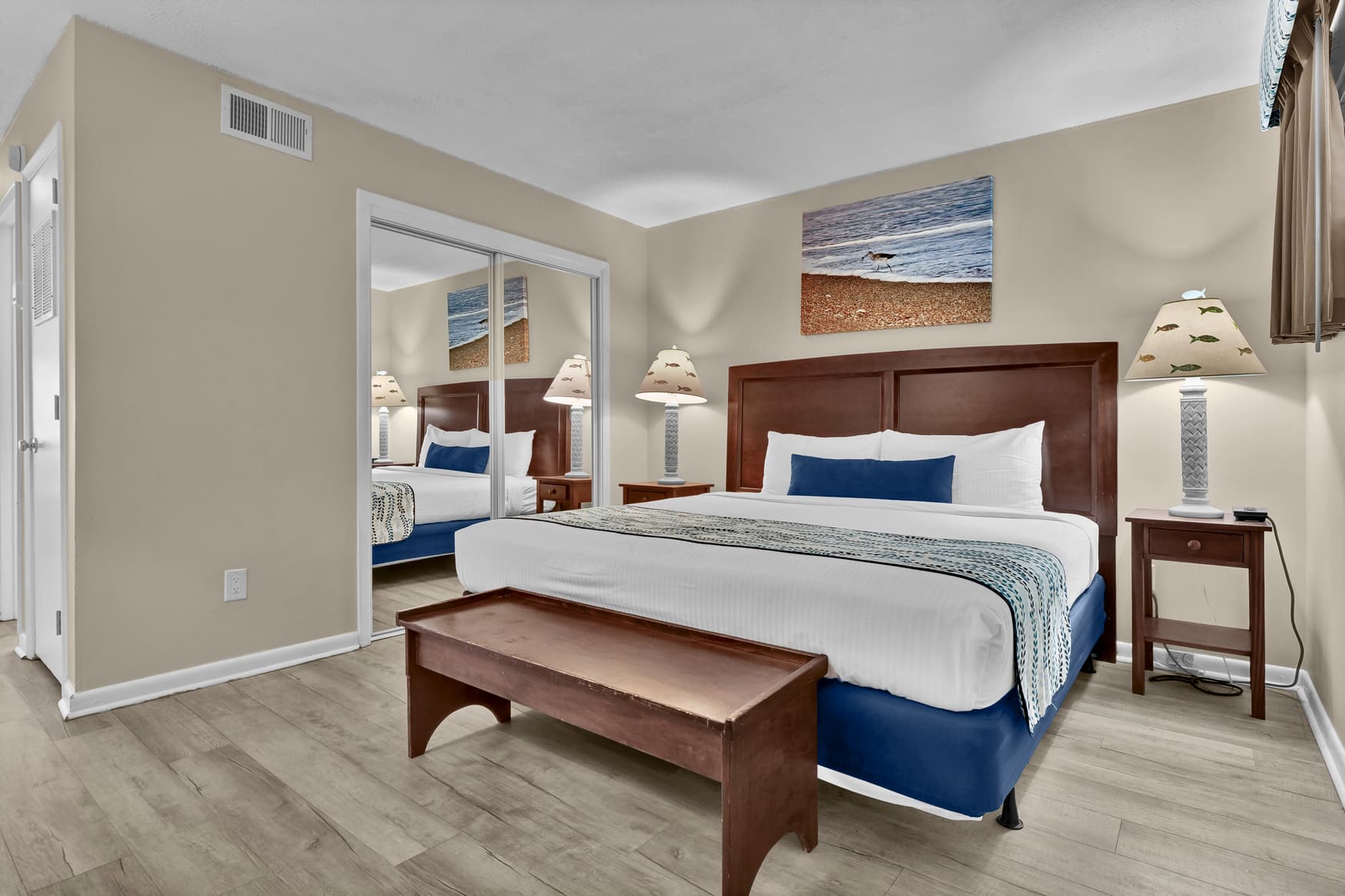 Sink into plush bedding and coastal comfort in your serene bedroom, where ocean artwork and warm lighting create the perfect retreat.