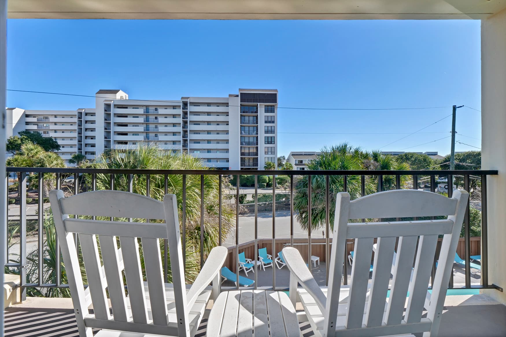 Relax on your private balcony with comfortable seating while enjoying tropical views and the sparkling pool below.