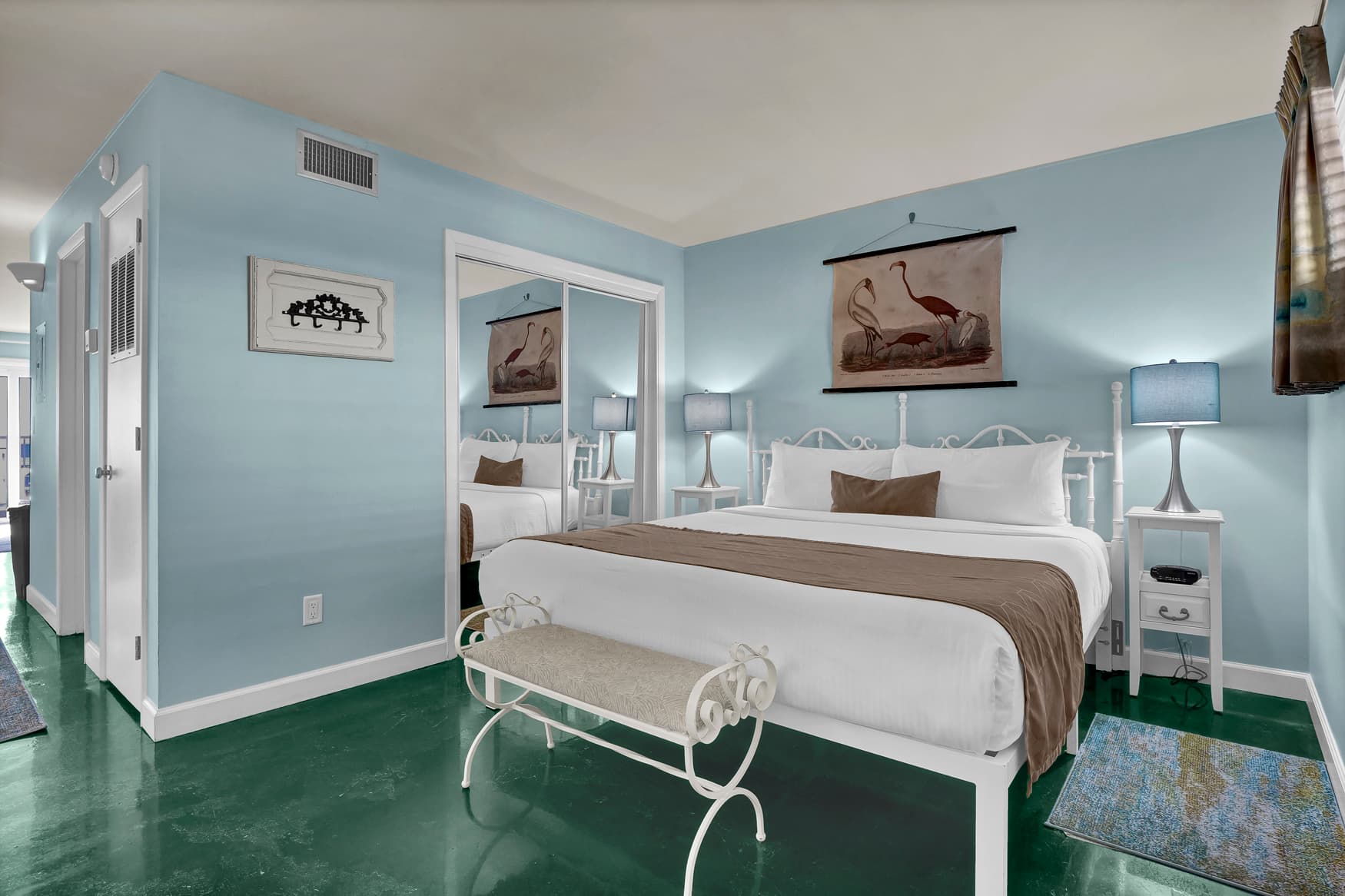 Drift off to sleep in this serene bedroom with coastal charm, featuring vintage bird artwork and calming blue walls.