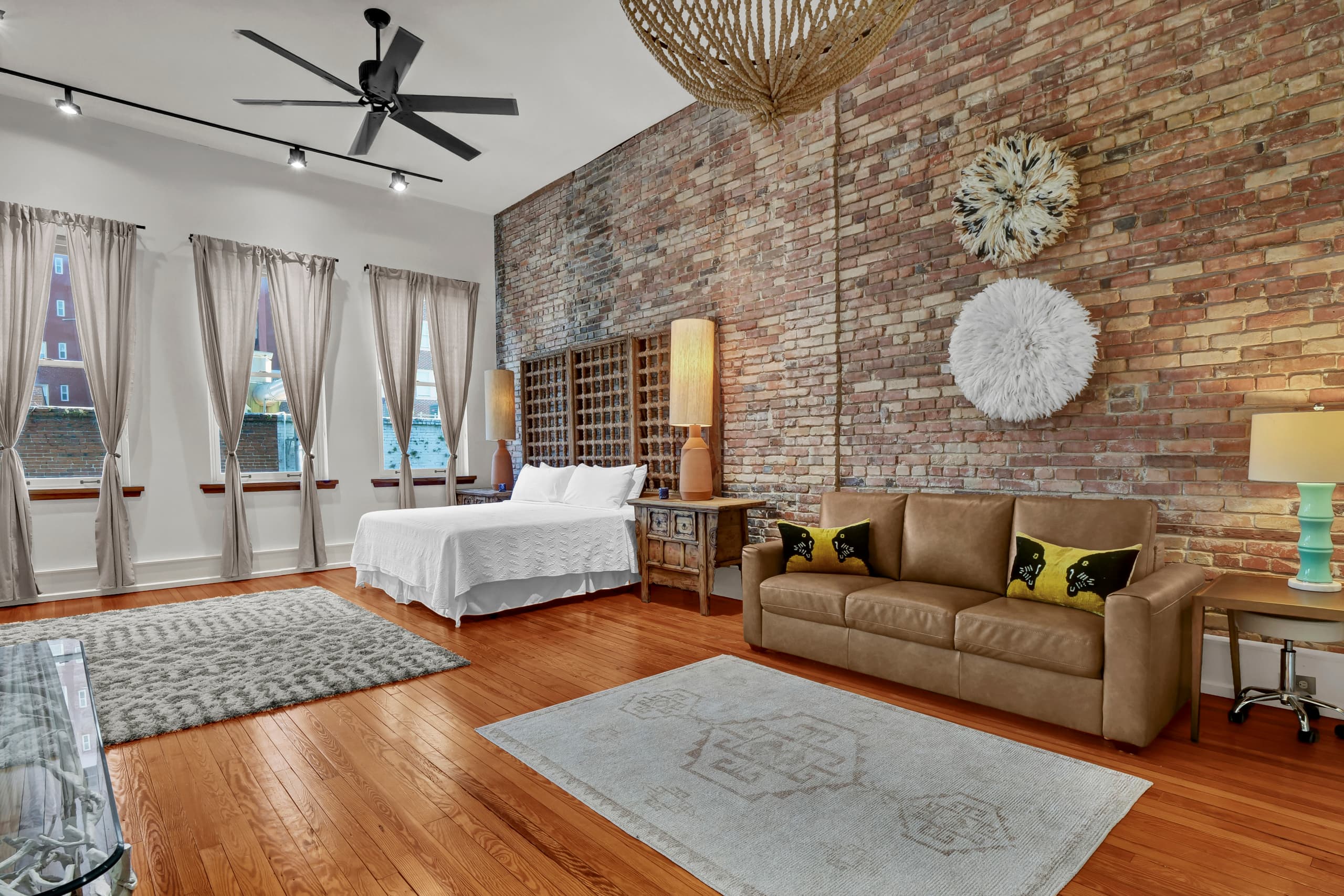 Relax in this stunning bedroom featuring exposed brick walls, soaring ceilings, and a cozy seating area perfect for unwinding after exploring the city.
