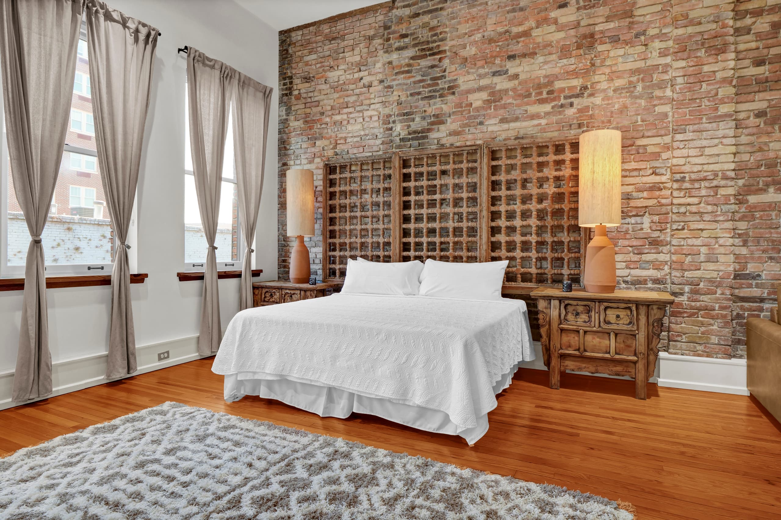 Drift into peaceful dreams surrounded by warm exposed brick and soft linens in your beautifully appointed bedroom.