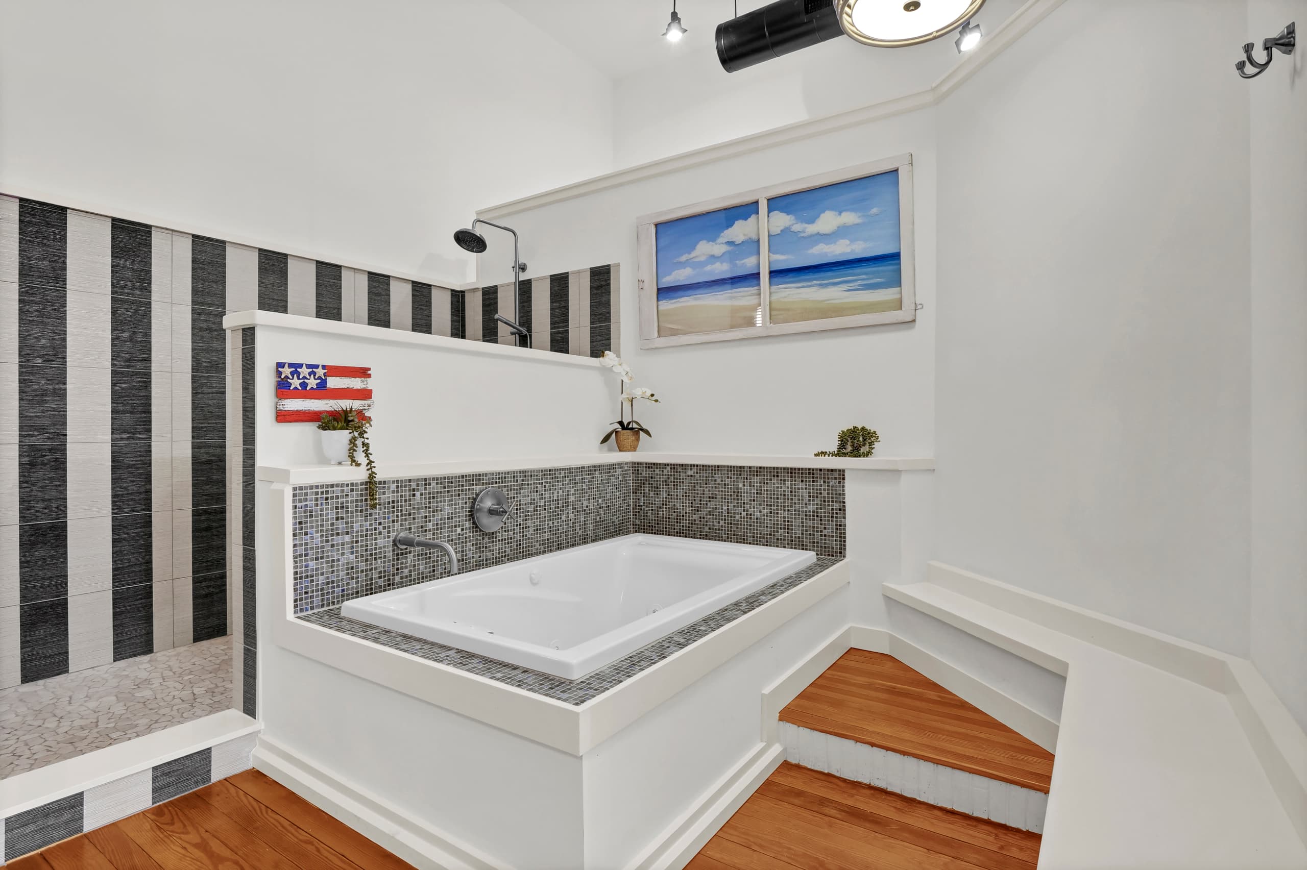 Sink into your stylish soaking tub surrounded by elegant mosaic tiles and ocean-themed décor for pure relaxation.