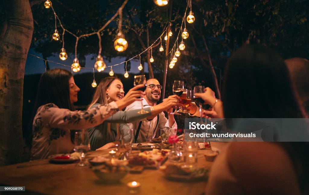 Friends toasting around a dinner party table by the coast