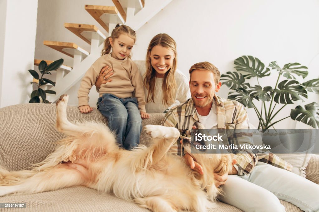 Family relaxing on a sofa at home with their golden retriever