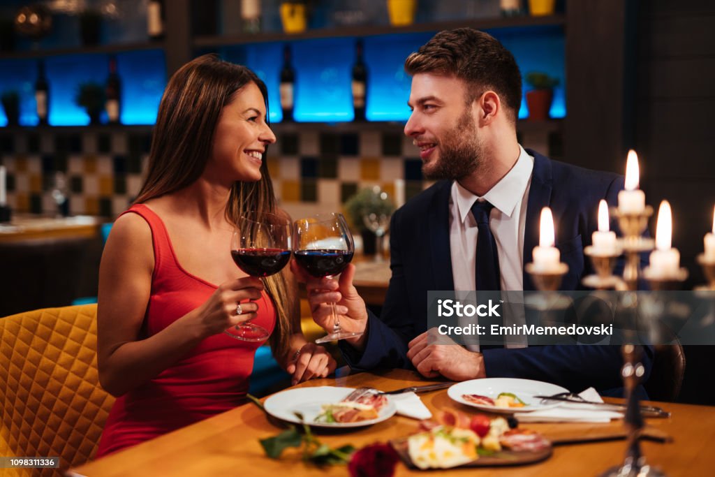 Couple enjoying red wine together over a candlelit dinner