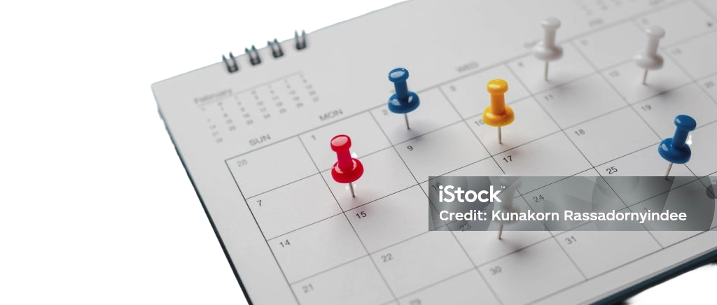 Calendar with colorful push pins marking event dates