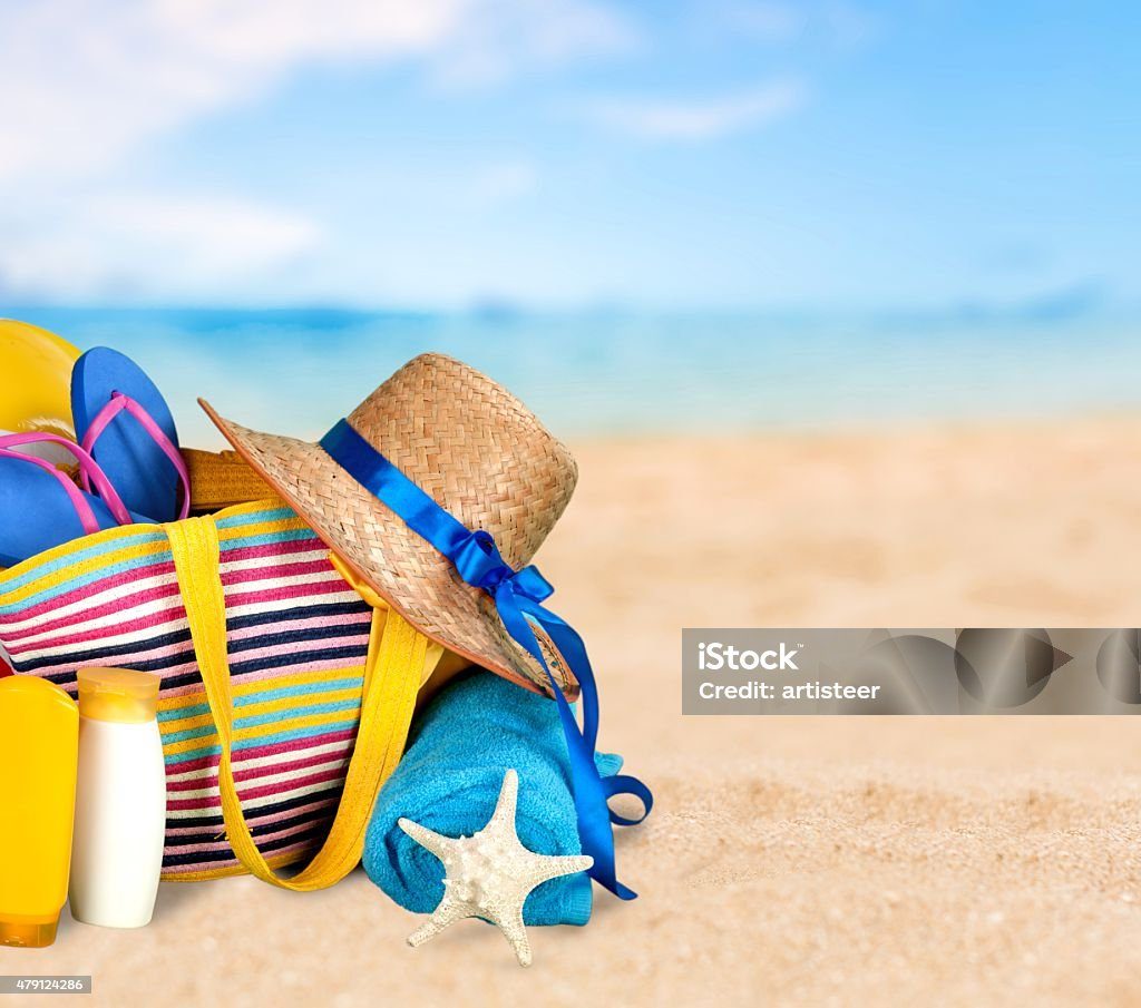 Beach bag with sun hat, starfish, and towels on the sand