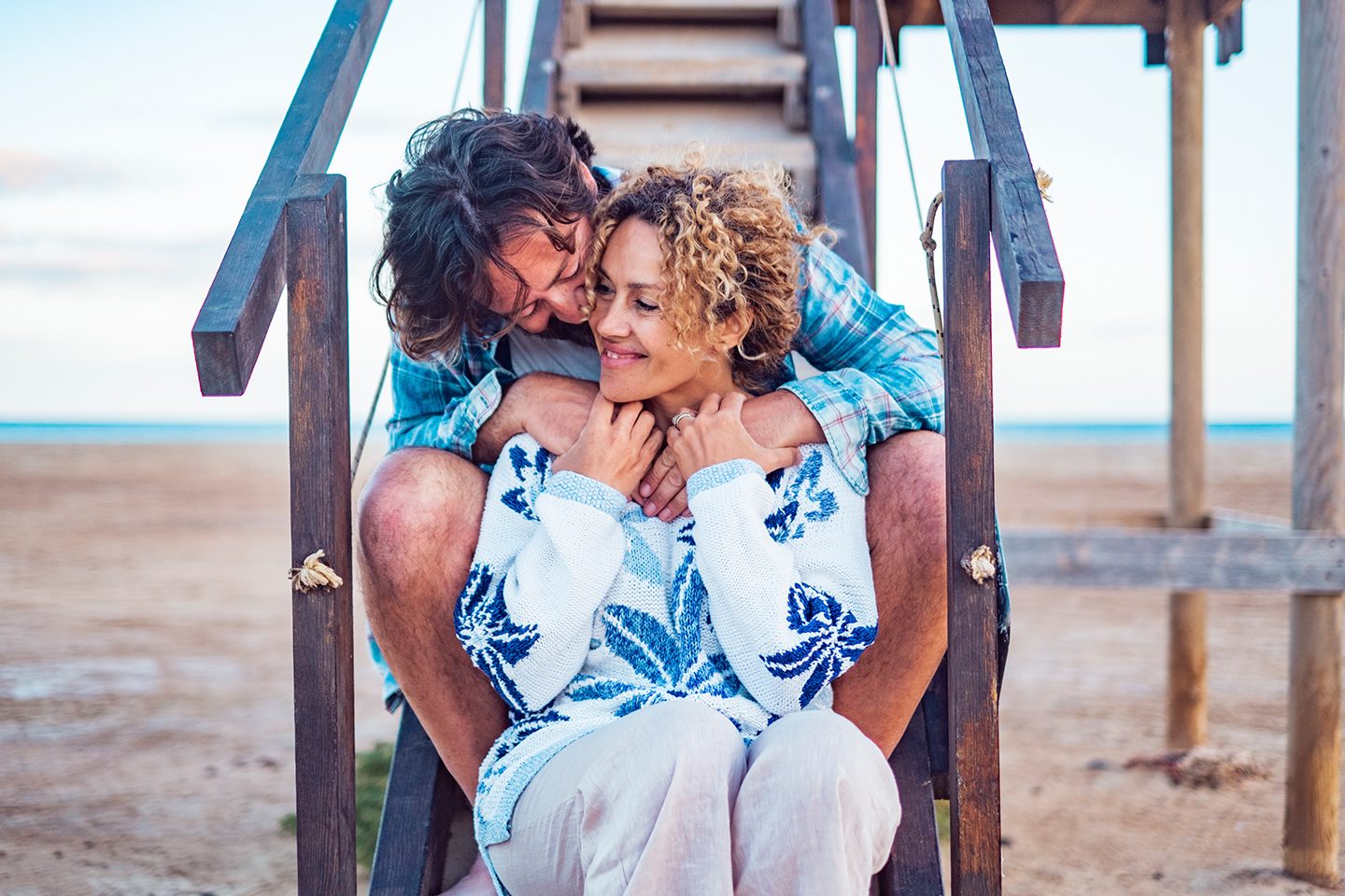 Couple relaxing together on the steps of a beach house