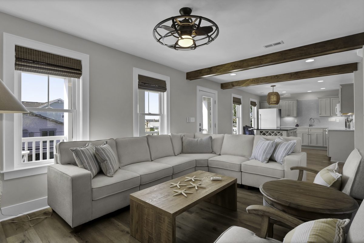 Bright coastal living room with plush sectional and open kitchen