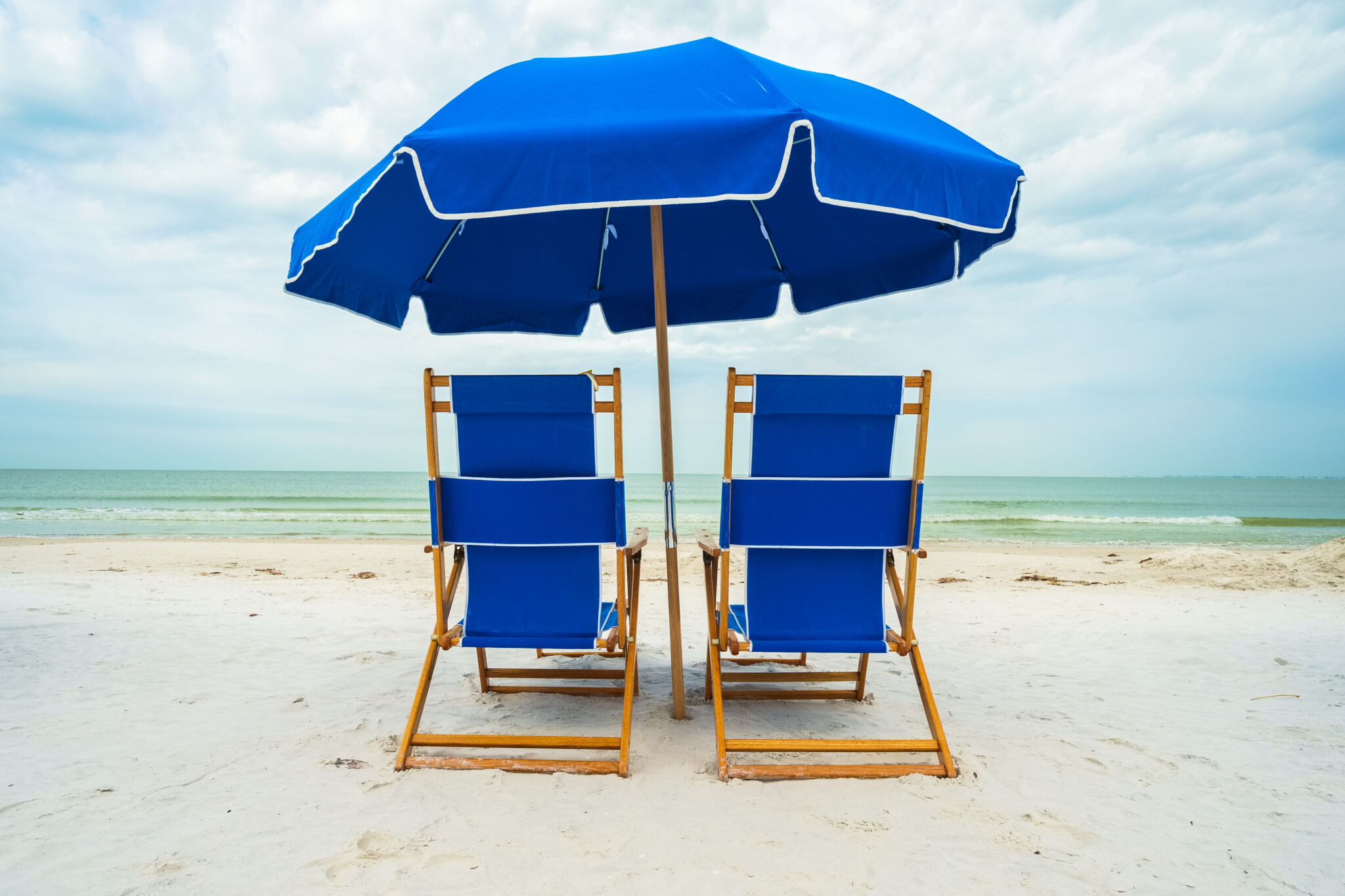 Blue beach umbrella and chairs on the sand